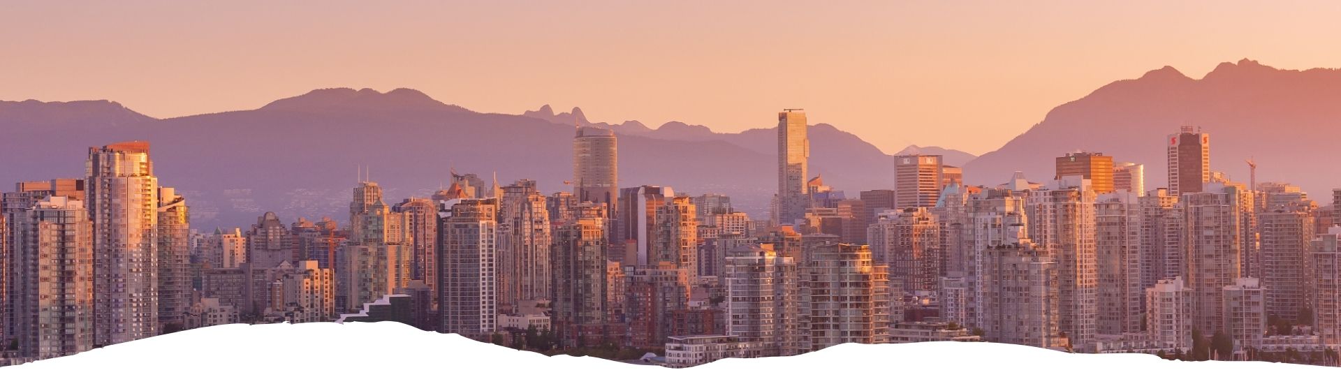 Panoramaansicht der Skyline von Vancouver mit Bergen im Hintergrund während des Sonnenuntergangs.