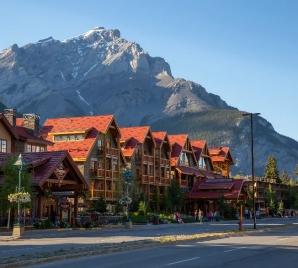 Hotelgebäude mit roten Dächern in Banff, umgeben von Bergen und Bäumen.
