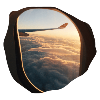 Blick aus einem Flugzeugfenster auf Wolken und den Flügel eines Flugzeugs bei Sonnenuntergang.