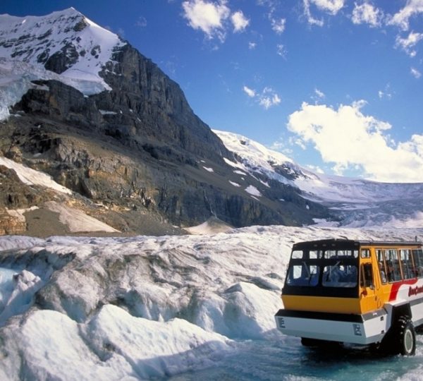 Ein geländegängiges Fahrzeug auf dem Columbia Icefield mit schneebedeckten Bergen im Hintergrund.