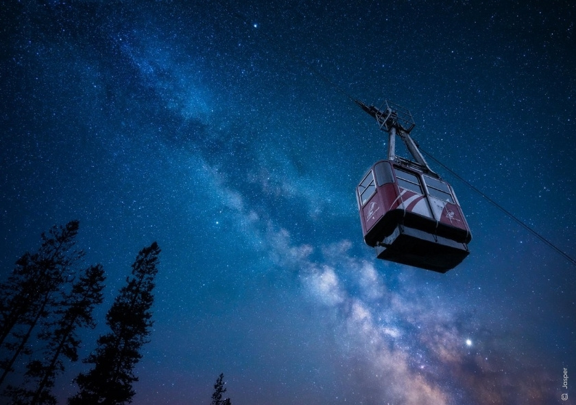 Seilbahn der Jasper Skytram schwebt unter einem klaren Sternenhimmel mit der Milchstraße.