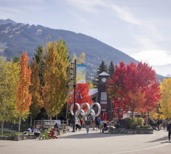 Herbstliche Szene in Whistler mit bunten Laubbäumen und einem Uhrenturm im Vordergrund.