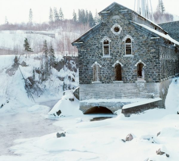 Ein historisches Steingebäude mit Fensteröffnungen, umgeben von Schnee und gefrorenem Wasser.