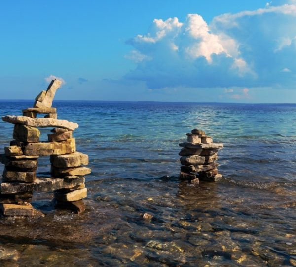 Zwei Steinmauern im Wasser des Lake Huron unter einem blauen Himmel mit Wolken.