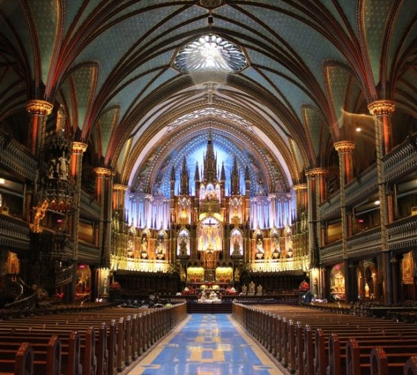Innenansicht der Basilika Notre-Dame mit bunten Fenstern und einer kunstvollen Decke.