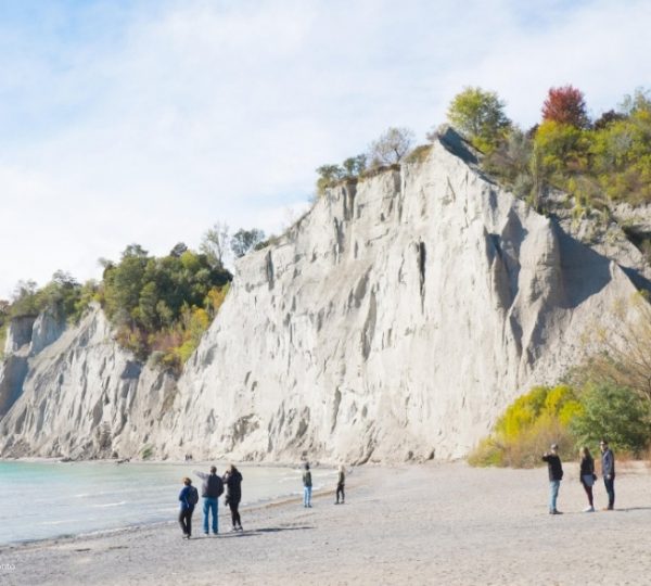 Granitklippen am Strand mit mehreren Personen, die entlang der Küste gehen.