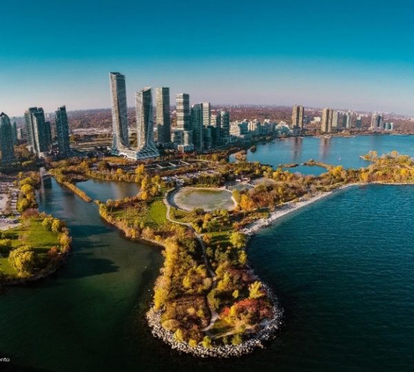 Luftaufnahme von Toronto mit modernen Gebäuden, Wasserflächen und Grünflächen im Vordergrund.