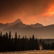 Berglandschaft mit rauchigem Himmel und untergehender Sonne in Kanada.