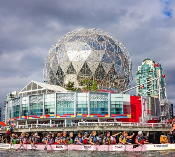 Dragonboot-Team paddelt vor dem Science World Gebäude in Vancouver mit einer großen geodätischen Kuppel. Kanada-Rundreise