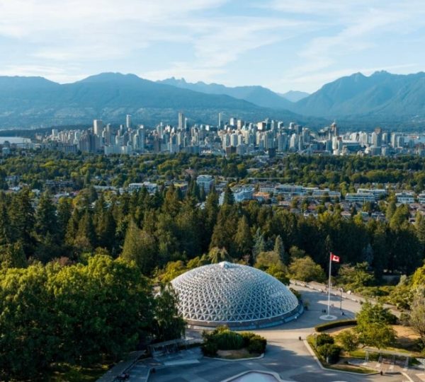 Luftaufnahme von Vancouver mit dem Bloedel Conservatory im Vordergrund und Bergen im Hintergrund. Kanada-Rundreise