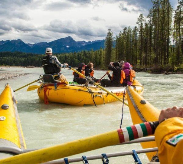 Eine Gruppe von Personen in einem gelben Raft auf einem Fluss in Westkanada während einer Rafting-Tour.