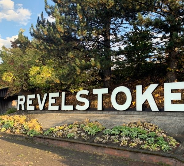 Großer Schriftzug mit dem Wort 'Revelstoke' vor einer grünen Landschaft mit Bäumen und Pflanzen. Kanada-Rundreise