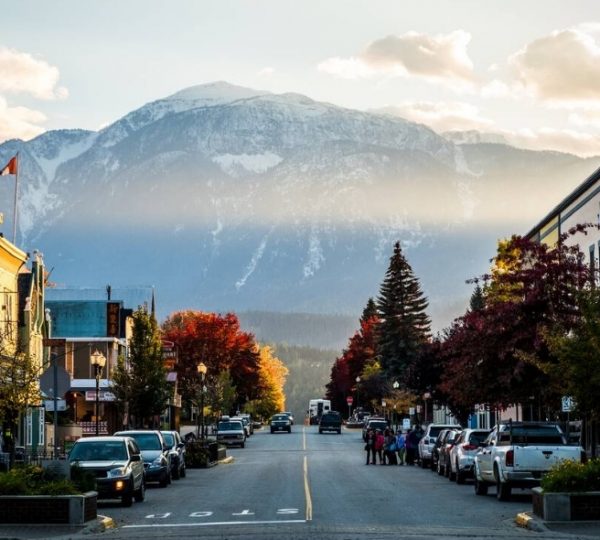 Blick auf eine Stadtstraße mit Geschäften und Bergen im Hintergrund während des Sonnenuntergangs. Kanada-Rundreise
