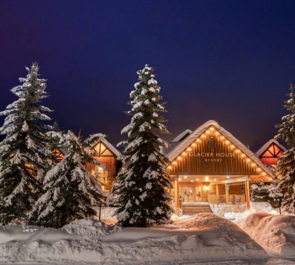 Glacier House Resort mit beleuchteter Fassade und schneebedeckten Bäumen in der Umgebung. Kanada-Rundreise