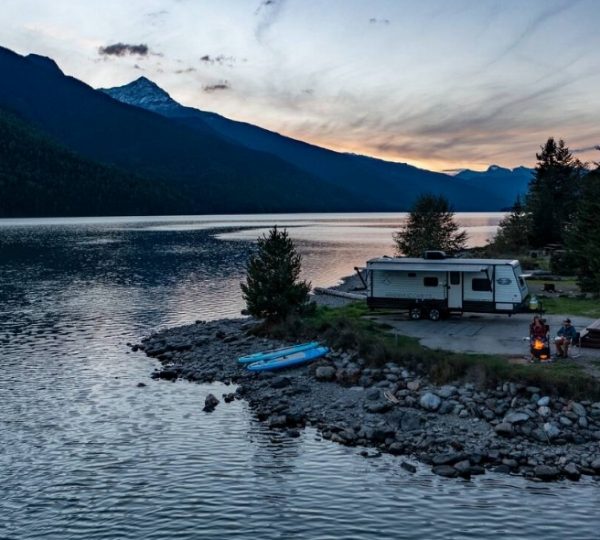Ein Wohnmobil steht am Ufer eines Sees in Westkanada, umgeben von Bergen und Bäumen.