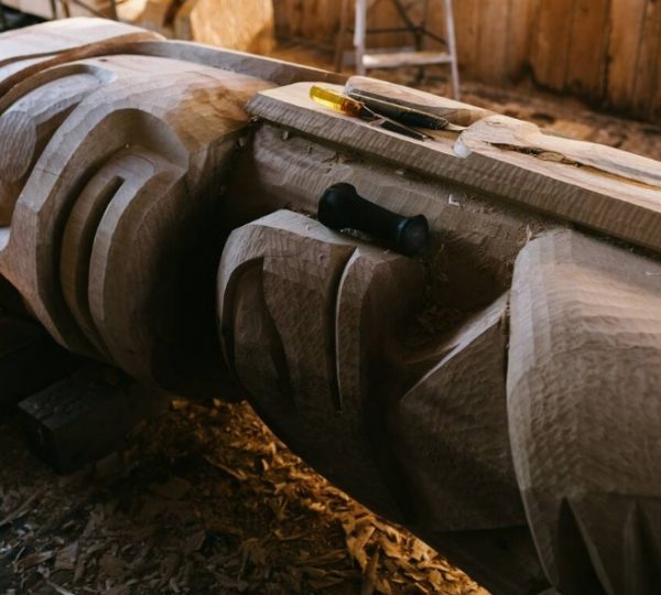 Unvollendete Holzskulptur mit Werkzeugen auf der Oberfläche in einer Werkstatt. Kanada-Rundreise