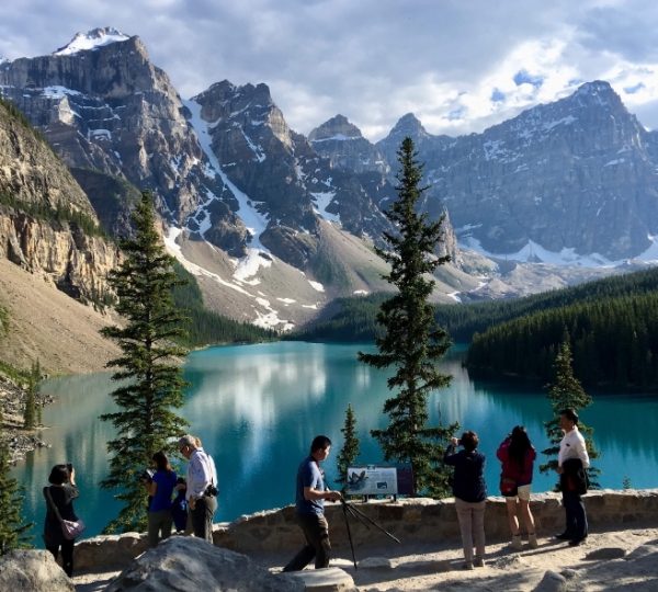 Berglandschaft mit einem klaren See und mehreren Personen, die die Aussicht genießen. Kanada-Rundreise