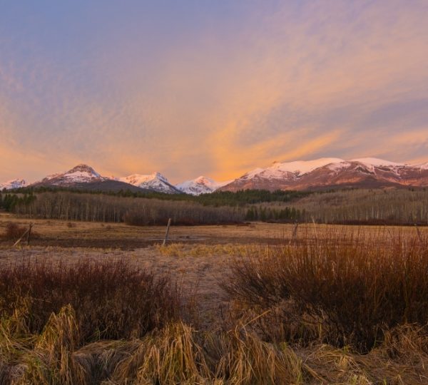 Berglandschaft mit schneebedeckten Gipfeln und einem farbenfrohen Himmel bei Sonnenuntergang. Kanada-Rundreise