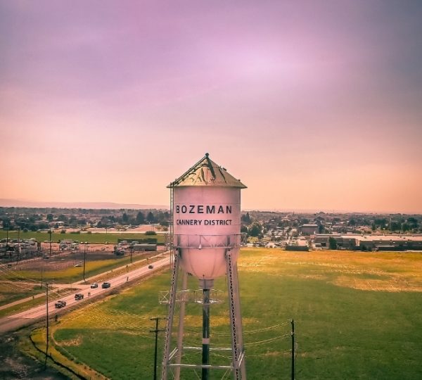 Wasserturm mit der Aufschrift 'Bozeman Cannery District' vor einer ländlichen Landschaft in Montana. Kanada-Rundreise