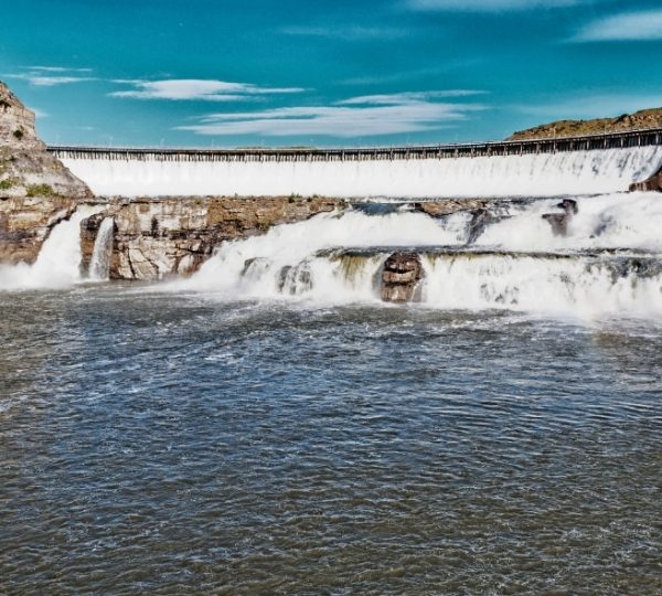 Wasserfall, der über einen Staudamm fließt, mit Wasser, das in den Fluss darunter stürzt. Kanada-Rundreise