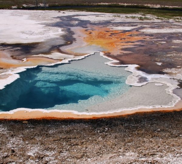 Eine heiße Quelle im Yellowstone Nationalpark mit klarem blauem Wasser und mineralischen Ablagerungen. Kanada-Rundreise