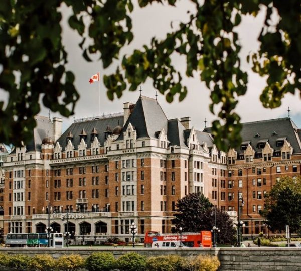 Das Fairmont Empress Hotel in Victoria, Kanada, mit einer markanten Architektur und dem kanadischen Flagge. Kanada-Rundreise