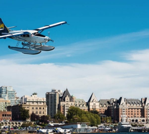 Ein Wasserflugzeug fliegt über die Stadt Victoria auf Vancouver Island mit historischen Gebäuden im Hintergrund. Kanada-Rundreise