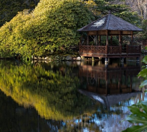 Holzpavillon am Ufer eines ruhigen Teichs im japanischen Garten von Hatley Park. Kanada-Rundreise