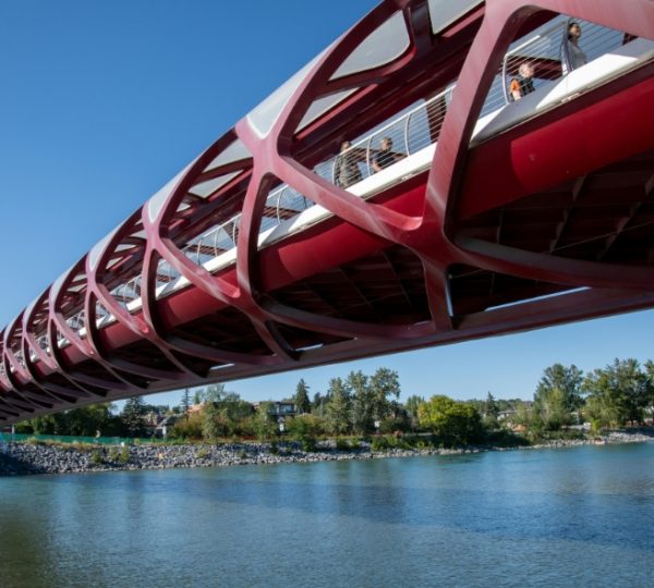 Die rote Fußgängerbrücke in Calgary, die über einen Fluss führt, mit Menschen auf der Brücke. Kanada-Rundreise