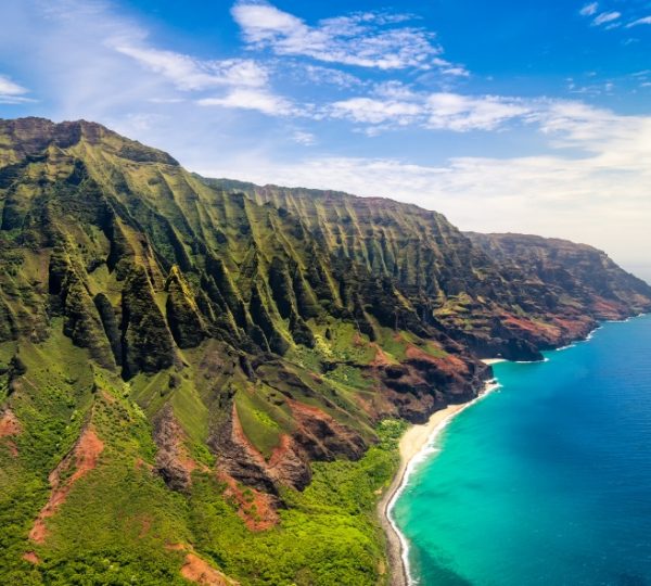 Luftaufnahme der Küstenlandschaft von Kauai mit grünen Bergen und klarem Wasser. Kanada-Rundreise