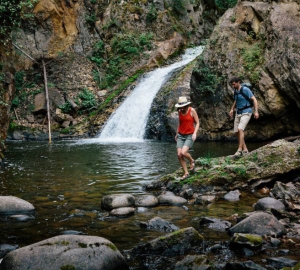 Zwei Wanderer gehen an einem Wasserfall entlang in einer natürlichen Umgebung in Westkanada. Kanada-Rundreise