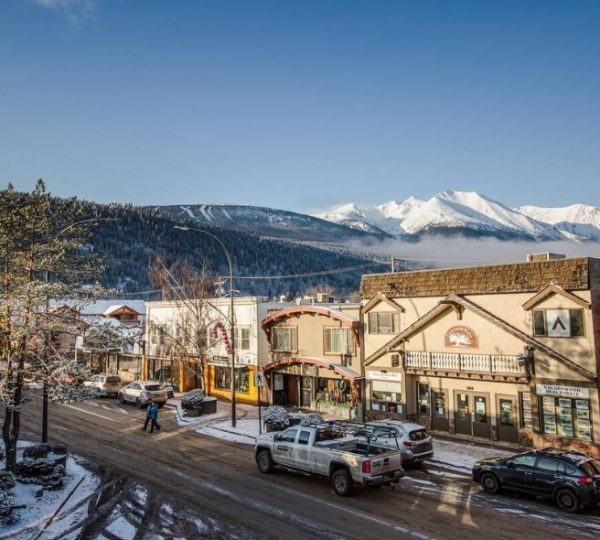 Stadtansicht von Smithers mit schneebedeckten Bergen im Hintergrund und Geschäften an der Straße. Kanada-Rundreise
