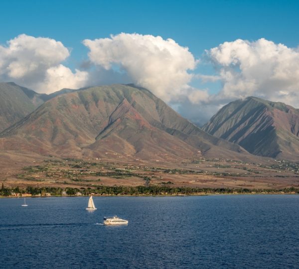 Berglandschaft mit mehreren Segelbooten auf ruhigem Wasser vor einer Küste. Kanada-Rundreise