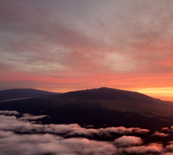 Landschaft mit Vulkanen und Wolken bei Sonnenuntergang, die orange und rosa Farben zeigt. Kanada-Rundreise