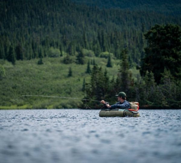 Ein Angler sitzt in einem Schlauchboot und fischt auf einem ruhigen See. Kanada-Rundreise