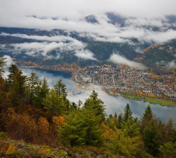 Luftaufnahme von Fort Nelson mit Blick auf den See und die umgebenden Berge. Kanada-Rundreise