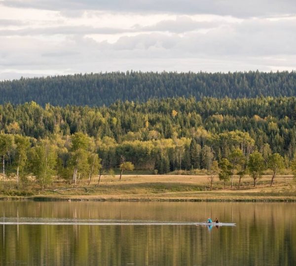 Ein Kajakfahrer paddelt auf einem ruhigen See, umgeben von Wald und Bäumen. Kanada-Rundreise