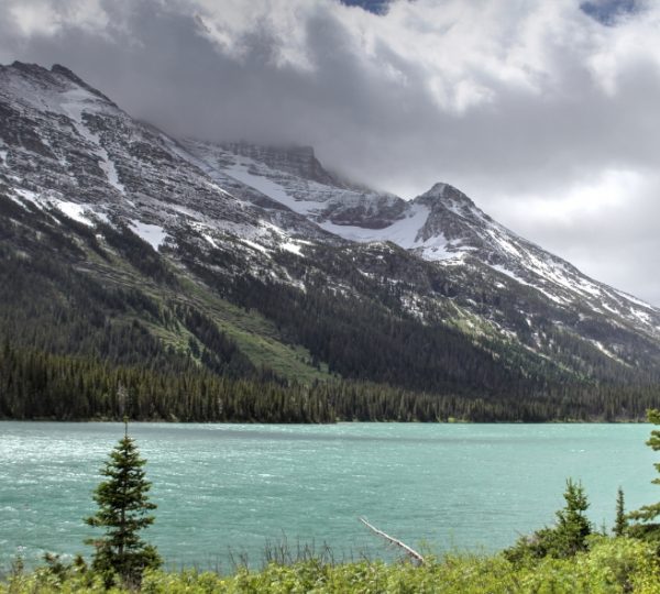 Berglandschaft mit schneebedeckten Gipfeln und einem türkisfarbenen See im Vordergrund. Kanada-Rundreise