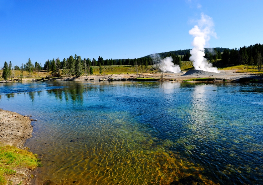 Klarer Fluss mit dampfendem Geysir.