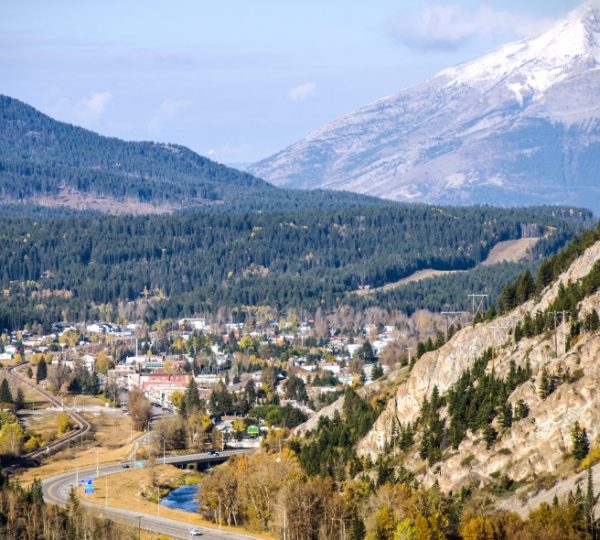 Blick auf Crowsnest Pass mit Bergen im Hintergrund und einer kleinen Stadt im Tal. Kanada-Rundreise