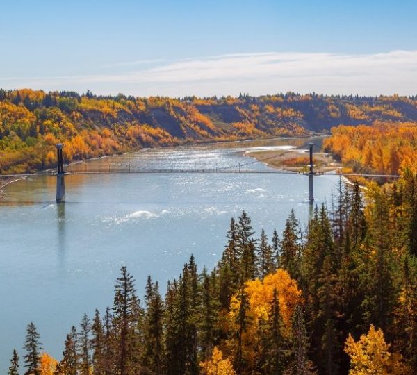 Westkanada Mietwagenrundreise Brücke über einen Fluss, umgeben von herbstlichen Bäumen in Edmonton. Kanada-Rundreise