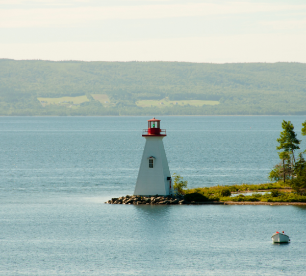 Ein Leuchtturm mit rotem Dach und weißem Turm, umgeben von Wasser in Baddeck, Ostkanada. Kanada-Rundreise
