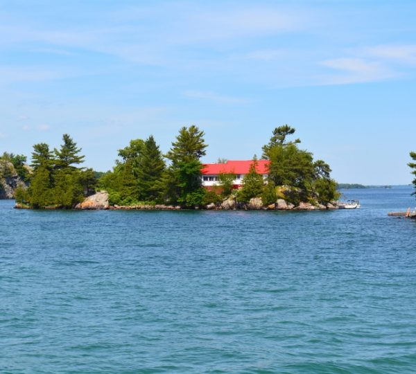 Ein rotes Haus auf einer kleinen Insel umgeben von Wasser und Bäumen in einer ruhigen Umgebung. Kanada-Rundreise