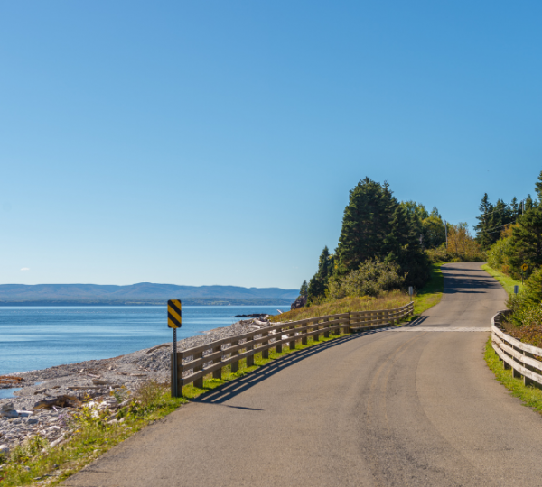 Kurvenreiche Straße entlang der Küste mit Blick auf das Wasser und die Landschaft in Ostkanada. Kanada-Rundreise