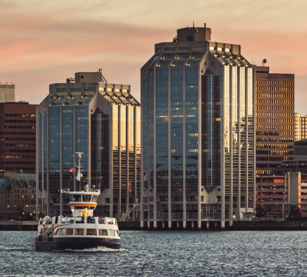 Fähre auf dem Wasser vor modernen Hochhäusern in Halifax bei Sonnenuntergang. Kanada-Rundreise
