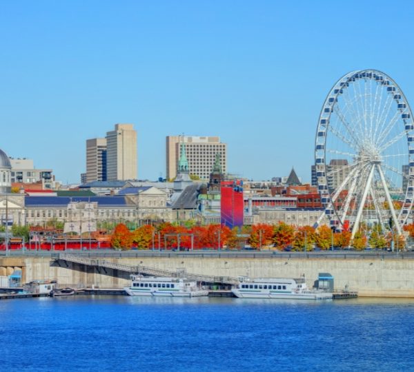 Stadtansicht von Montreal mit einem Riesenrad und bunten Bäumen im Vordergrund. Kanada-Rundreise