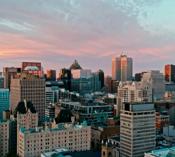 Blick auf die Skyline von Montreal mit modernen und historischen Gebäuden unter einem farbenfrohen Himmel. Kanada-Rundreise