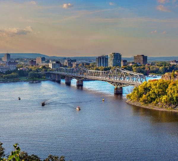 Blick auf die Stadt Ottawa mit einer Brücke über den Fluss und Booten auf dem Wasser. Kanada-Rundreise