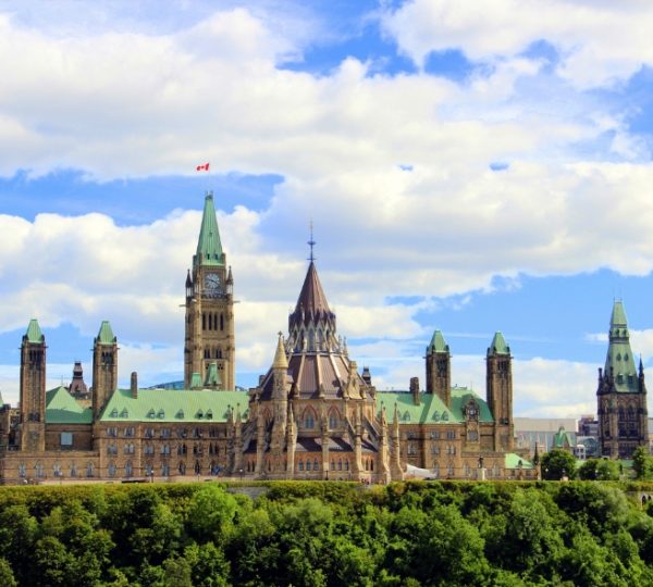 Kanada Osten Rundreise: Das Parlamentsgebäude in Ottawa mit markanten Türmen und grünen Dächern unter einem bewölkten Himmel. Kanada-Rundreise