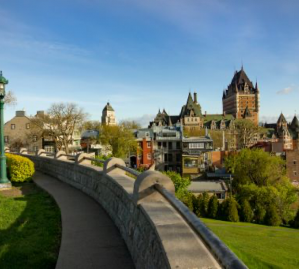 Entdecken Sie diesen Kanada Road Trip: Panoramaansicht von Quebec mit historischen Gebäuden und einer Mauer im Vordergrund.